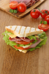 Tasty sandwich with ham on wooden table