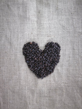Organic roasted coffee beans in a heart shape on a burlap sack. 
