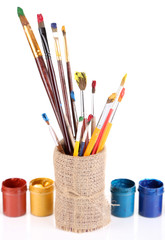 Brushes with paints in vase isolated on white