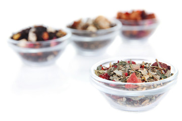 Different kinds of dry tea in bowls isolated on white