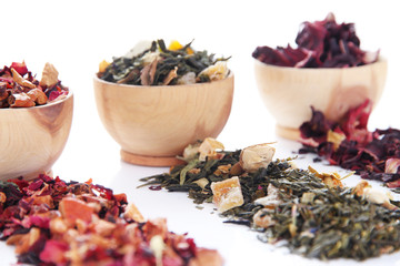 Different kinds of dry tea in bowls isolated on white