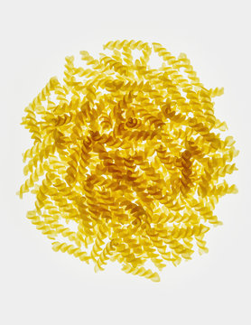 Pile of organic gluten free fusilli pasta spirals, white background