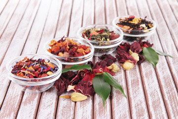 Aromatic dry tea in bowls on wooden background