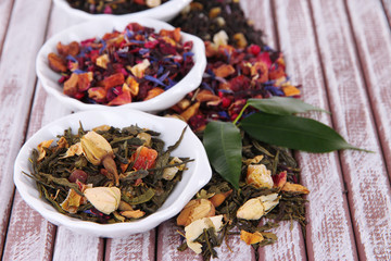 Aromatic dry tea in bowls on wooden background