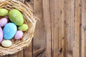 Easter eggs in nest on color wooden background