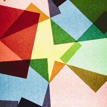 Multi-colored pieces of recycled construction paper. Shapes, triangles and different colours, above a light source.