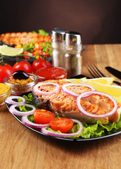 Tasty grilled salmon with lemon and vegetables, on wooden table