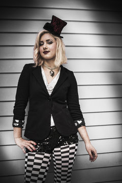 A young woman wearing a black top hat perched on the side of her head, and a black jacket. Circus clothes.