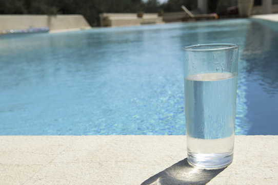 Glass of water on the side of a swimming pool