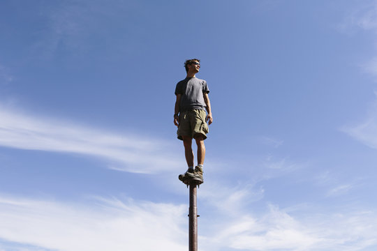 Man standing and balancing on a metal post, looking towards expansive sky, Surprise Mt, Alpine Lakes Wilderness, Mt. Baker-Snoqualmie NF -