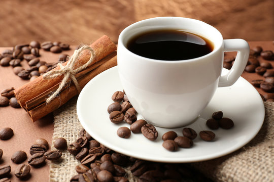 Coffee beans and cup of coffee on table on brown background