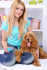 Beautiful young woman with cocker spaniel in room