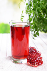 Ripe pomegranates with juice on table on light background