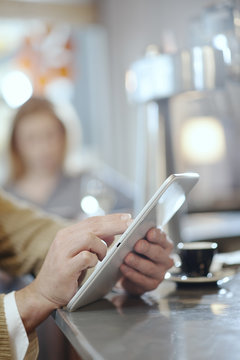 closeup on man's hands using a digital tablet in a bar