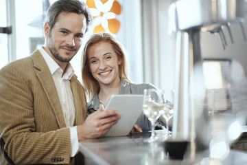 handsome young couple in a bar using a digital tablet