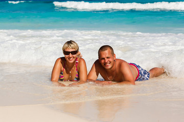 Young romantic couple laying on sandy beach