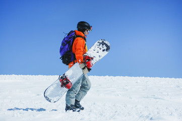 Fototapeta na wymiar Snowboarder walking at the mountains