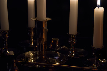 Multiple white burning candles in brass holders