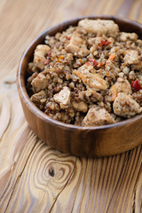 Stewed buckwheat and chicken fillet in a wooden bowl, close-up