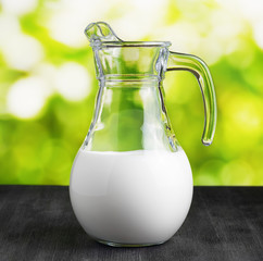 Jug of milk on nature background. Half full pitcher