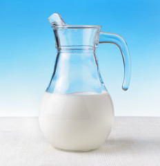 Jug of milk on sky background. Half full pitcher