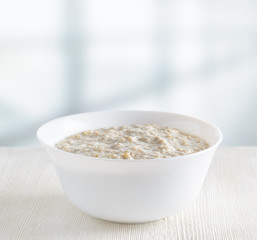 Bowl of oat porridge on wooden table