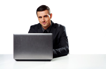 Happy businessman sitting at the table with laptop 