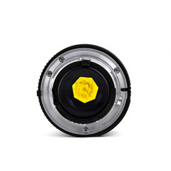 Camera lens with yellow flower behind lens aperture.