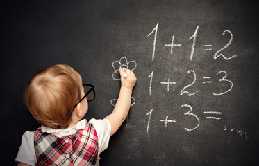 baby girl pupil draws a chalk on blackboard