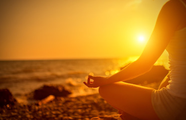 hand of  woman meditating in a yoga pose on beach at sunset