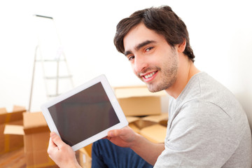 Handsome young man in his new flat using tablet