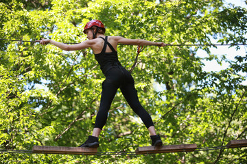 woman climbing in adventure rope park in safety equipment