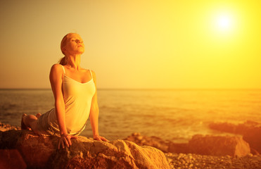 woman doing yoga on the beach at sunset