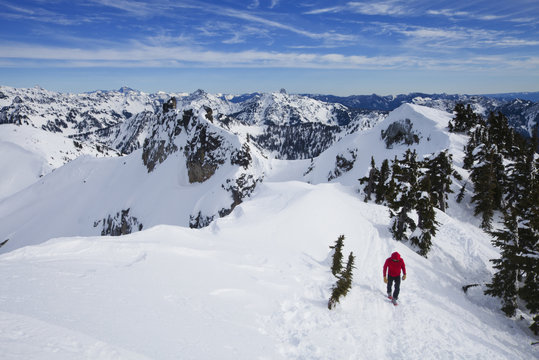 A climber in a red jacket on the summit of Snoqualmie Peak in the Cascades range of mountains in Washington state, USA.