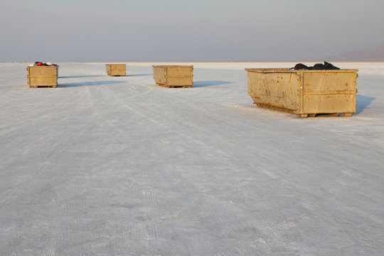 Large garbage containers on salt flats, dusk