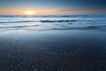 sunset over sand beach at low tide on North sea