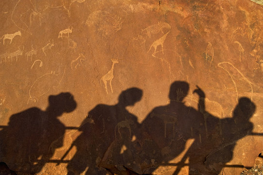 The shadows of tourists at a viewing point, on the surface of the rock at  Twyfelfontein World Heritage Site at Uibasen Conservancy, Damaraland, Namibia.
