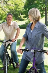 Obraz premium Loving couple riding bicycles in park