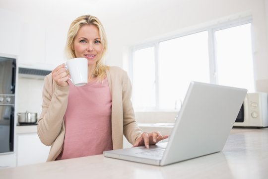 Portrait of beautiful woman with coffee cup using laptop in