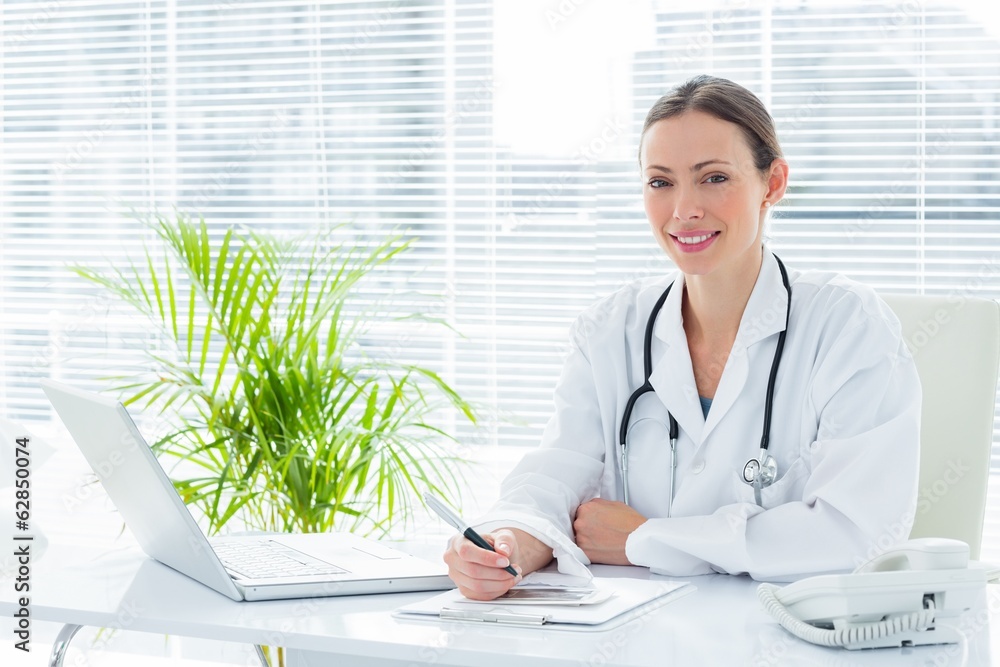 Wall mural smiling doctor at desk in clinic