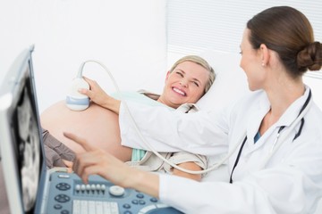 Obraz premium Happy female doctor showing woman her baby on ultrasound