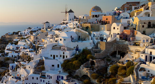 The windmills of Santorini in Greece. A hilltop town of whitewashed houses. Sunset. 