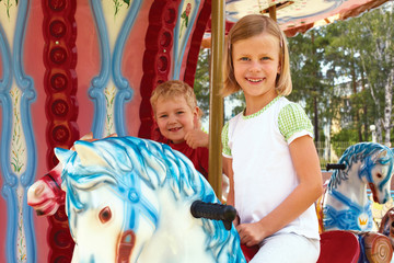 Fototapeta na wymiar boy and girl ride on the carousel