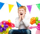 Surprised little redhead boy among birthday balloons