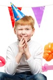 Little redhead boy in birthday paper hat