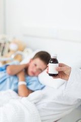 Doctor holding cough syrup with boy in hospital