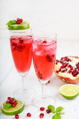 Two glasses with red pomgranate champagne, lime and mint.