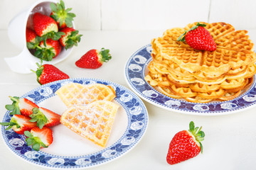 Crisp golden fresh baked waffle topped with strawberries on whit