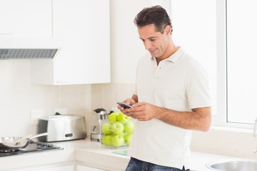 Side view of a man text messaging in kitchen