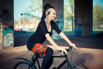 Obraz na płótnie Canvas young beautiful punk dark girl riding bike